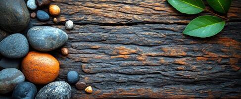 Natural stone and wood design. Various smooth stones are arranged on rustic wooden surface, with green leaves enhancing the natural appearance. photo