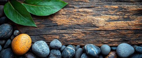 Stones and wood for tranquility. Smooth stones lie beside a weathered wood surface, contrasted by vibrant green leaves. photo
