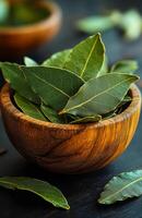 Bay leaves in wooden bowl. Fresh bay leaves are arranged in a rustic wooden bowl, highlighting their vibrant green color against a dark background. photo