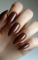 Elegant brown manicure with pointed tips. Close-up of manicured hands with glossy brown pointed nails, highlighting stunning nail art. photo