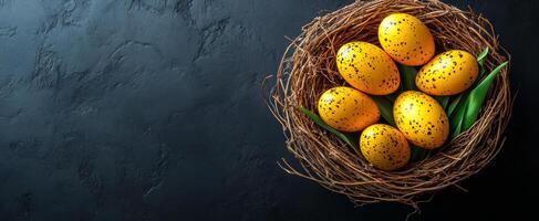 Colorful eggs arranged in a rustic nest. A nest made of twigs holds six vividly speckled yellow eggs on a dark surface with green leaves. photo