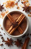 Spices artfully arranged in a bowl. A bowl filled with brown sugar and cinnamon sticks, accented by star anise and resin pieces, creating a rich display. photo