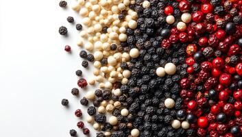 Vibrant mix of pepper types. A vibrant collection of assorted peppercorns spread on a white surface, showcasing different sizes and colors. photo