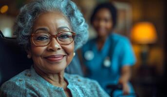 A woman in a blue shirt and glasses is smiling at the camera. A nurse is standing behind her photo
