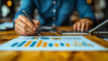 A man is writing with a pen on a piece of paper. The paper has a lot of numbers and graphs on it. The man is focused on his work and seems to be in a serious mood photo