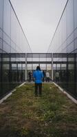 A person standing in front of a glass building photo