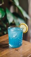 Blue cocktail with lemon slice on top of a wooden table photo