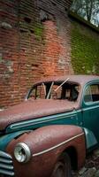 An old car is parked in front of a brick wall photo