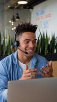 A man wearing a headset and smiling while using a laptop photo