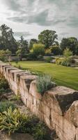 A stone wall in a garden with a lawn and trees photo