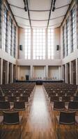 Empty auditorium with rows of chairs and windows photo