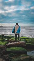 Man standing on rocks at the ocean photo