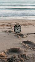 An alarm clock sitting on the beach near the ocean photo