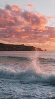A sunset over the ocean with waves crashing into the shore photo