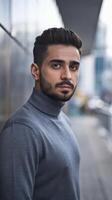 A man in a turtle neck sweater standing in front of a building photo