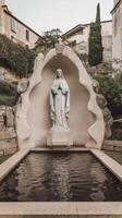 A statue of mary in a small pond in front of a building photo