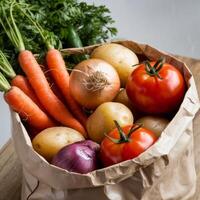 A paper bag filled with vegetables and potatoes photo
