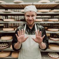 A man in a white hat and apron is making a gesture with his hands photo