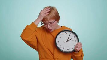 Woman in glasses with anxiety checking time on clock, running late to work, being in delay, deadline video
