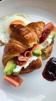A croissant with ham, avocado and egg on it photo