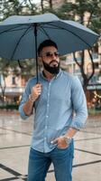 A man with a beard and sunglasses holding an umbrella photo
