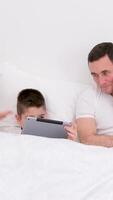 comfortable soft white bed husband wife with child and tablet teach son home schooling difficulties solve problems mother and father hold heads not understanding How to teach child family of three video