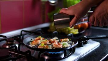 add black pepper to the shrimp Seafood meal recipe. Seasoning and spicing food. Chef adding pepper to shrimp in frying pan video