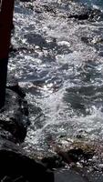 Bougainvillea boat on the ocean shore, waves are beating against its side, against the rocks, running aground video