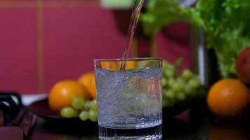 pour water into a glass with fruits in the background fresh grape fruit juices in the glass for drinking healthy concept background footage video