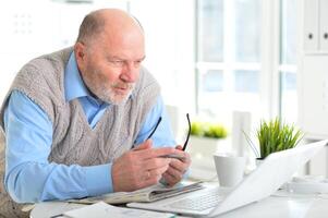 Portrait of an elderly man using a laptop in an office photo