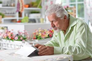 Elderly man posing at a table with a tablet photo