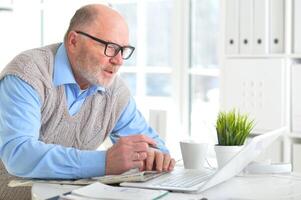 Portrait of an elderly man using a laptop in an office photo