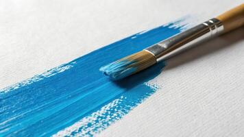 A brush with blue paint on a white canvas photo