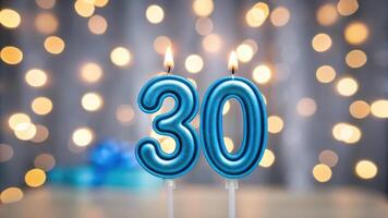 Blue birthday candles with number 30 in front of blurred bokeh lights background photo