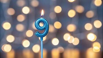 Blue birthday candle with number 9 on blurred background photo