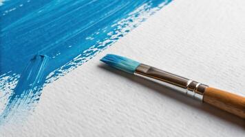 A brush with blue paint on a white canvas photo