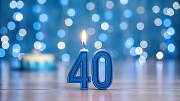 Blue birthday candle with number 40 in front of blurred background photo