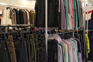 Clothing store interior with racks of apparel. Display of fashion items in retail space, variety and choice for shoppers. Neatly organized clothes, variety of garments. Closet organization and retail photo