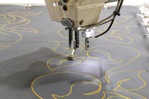 Sewing machine needle in action, stitching yellow thread on gray fabric. Close-up view of the needle and thread, showcasing the precision and detail of sewing photo