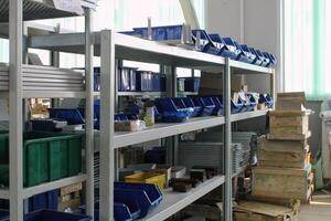 Metal shelf with various storage bins and containers, showcasing organization and storage solutions. Industrial or warehouse setting with a focus on organization and utility photo