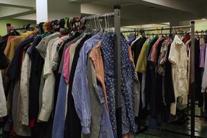 Close-up of rack of colorful clothes hanging in row with variety of textures and styles. Fashion and personal style, diversity of clothing and individual expression. Retail or wardrobe management photo