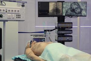 Advanced medical procedure in modern room with high-tech equipment and monitoring systems for care. Patient lies on surgical table in operating surrounded by monitors with vital signs and imaging data photo