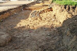 Trench excavation with exposed pipes or cables at a construction site. Earthwork, infrastructure, and urban development concept photo
