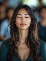 Asian woman meditating with closed eyes relaxing during yoga class photo