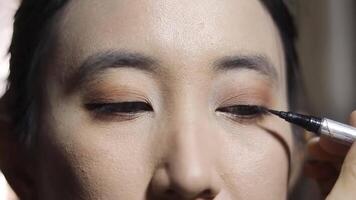Close-up view of a woman carefully applying black eyeliner, enhancing her eyes with precise strokes for a captivating and beautiful look. video