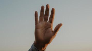 Hand raised against a sunset background showcasing human expression and connection. photo