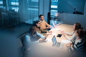 A diverse team of young professionals collaborates in a modern office conference room. Businesspeople discuss strategy, technology, and planning, using laptops to develop an innovative e-commerce photo