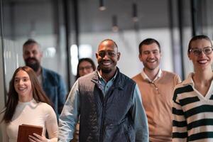 Business team in a modern open space startup office walking together. Diverse group of businesspeople smiling while having a discussion. Successful mixed race colleagues collaborating on a new project photo