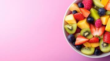 Fresh Colorful Fruit Salad in White Bowl on Pink Background photo
