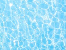 Serene light blue water surface with vibrant sun-dappled reflections. Gentle ripples create pattern photo